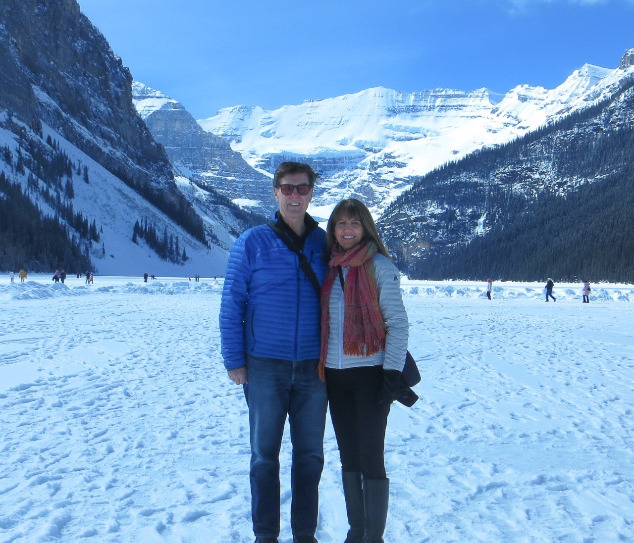 Brenda Hogan stands smiling with her fiance in a snowy landscape with snow covered mountains in the background.